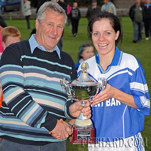 The chairman of the Ladies Football County Board, Enda McDonald, hands over the cup to Fethard's captain after their tiumph over Emly in the Junior County Final.