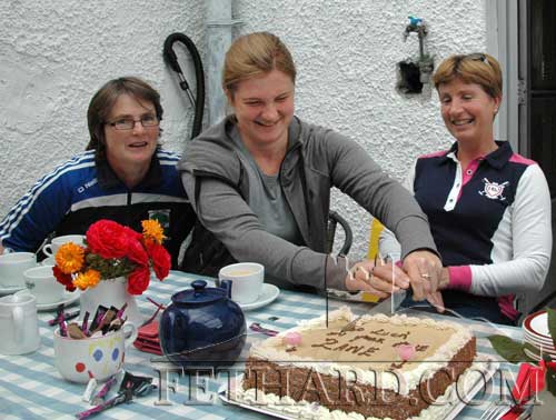 Zane Zorina (centre) cutting a cake supplied by her friends in Fethard Athletic Club at a farewell coffee morning to mark her departure from Fethard. Also included are Noreen Sheehy (left) and Ginny Hutton.