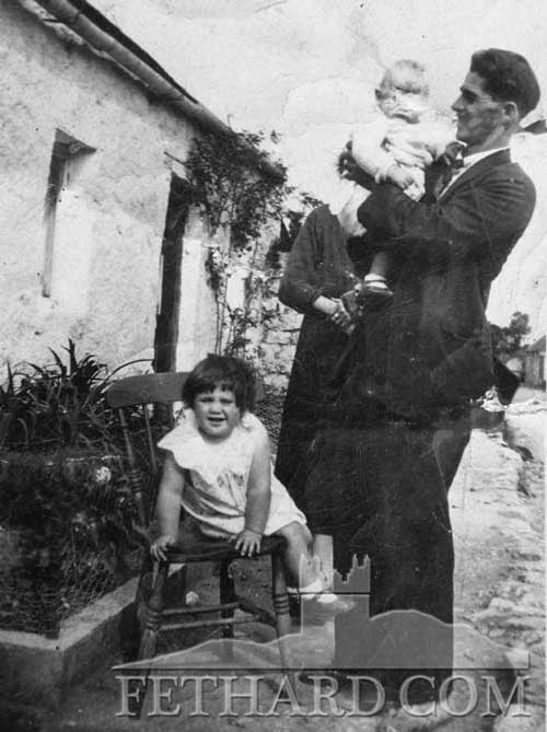 Harry Sayers holding John (Buddy) Sayers with Catherine Sayers (John's daughter) on chair. Taken outside old home in the Valley. John was on holiday from America. Catherine lives USA.