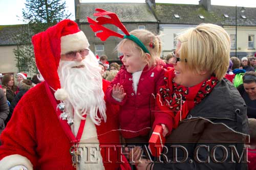 Santa meeting Lizzie Purcell and her daughter Bonnie on The Square, Fethard, last year. Santa returns to Fethard this year on Friday, December 11, and will will visit the schools at lunch time followed by switching on the Christmas lights on The Square.