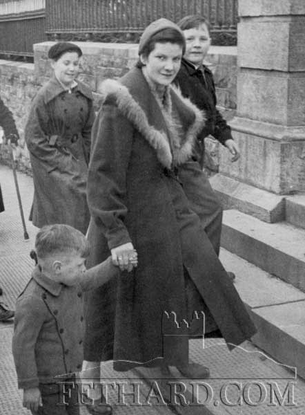 Mrs Lizzie Sheehan, St. Patrick's Place, holding her son Pat Sheehan's hand. In the background are, Helen Fergus (left), Cashel Road, and Michael Mackey, Cahir Road.
