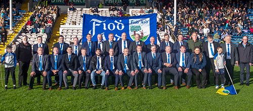 Back Row L to R: Tristan Byrne (flag holder), Danny Keane (selector), Michael Carroll, Eugene Walsh, Brendan Brett, Tom Bourke, Chris Coen, Willie Quigley, Brian Burke, Micheál Spillane, Willie O’Meara, Michael Quinlan, Stephen O’Donnell, Michael O’Riordan, Noel Byrne (selector), Miceál McCormack (secretary), Michael Healy (selector). Front L to R: seated, Thomas McCarthy, Tomás Keane, John Paul Looby, Michael Fitzgerald, Tommy Sheehan (junior), Jimmy O’Meara, Martin Coen, Willie Morrissey, Philly Blake, Michael Ryan, Ms Fitzgerald, and young flag bearer.