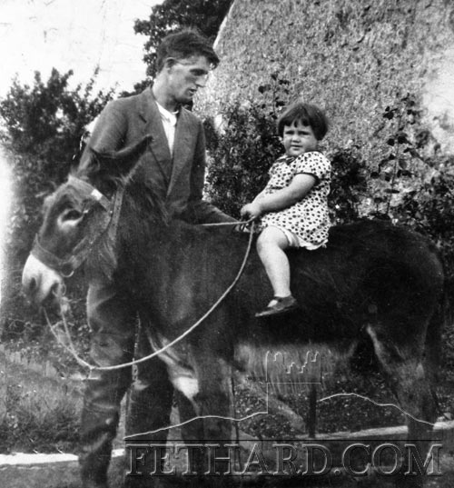 Patrick Sayers photographed holding a child taking a ride on an ass.